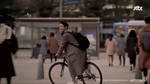 a man wearing a coat is riding his bike down the street
