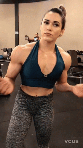 a woman standing with arms out in a gym