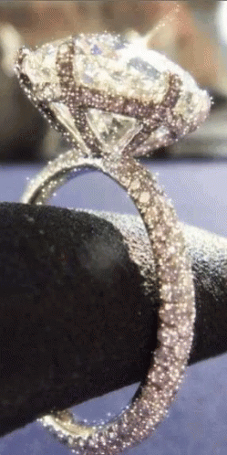 the diamond ring on top of a black rock is being held by someone