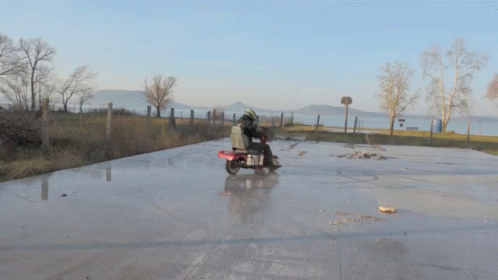 a person riding on the back of a motorcycle on a wet road