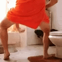 man in blue towel doing a handstand next to a white toilet