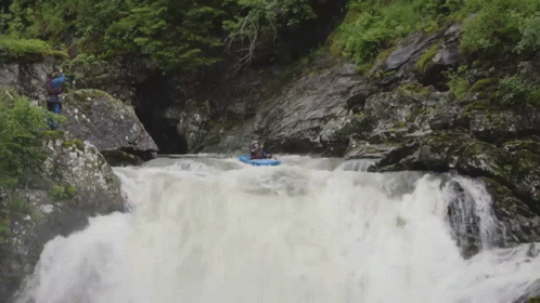 people are rafting down a very big waterfall