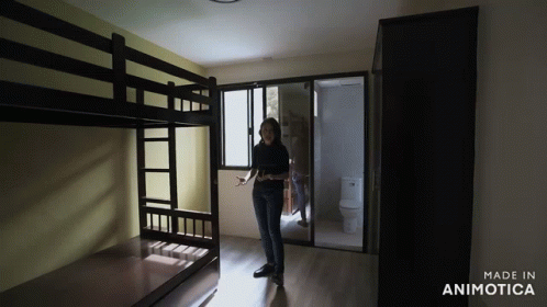 a woman is standing in a dark room while standing near bunk beds