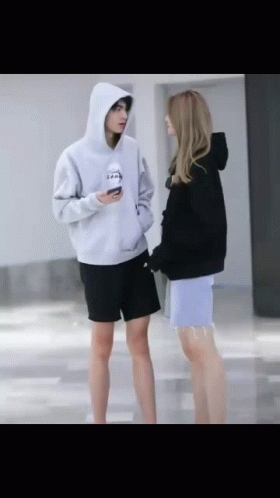 two girls standing around looking at their cell phones