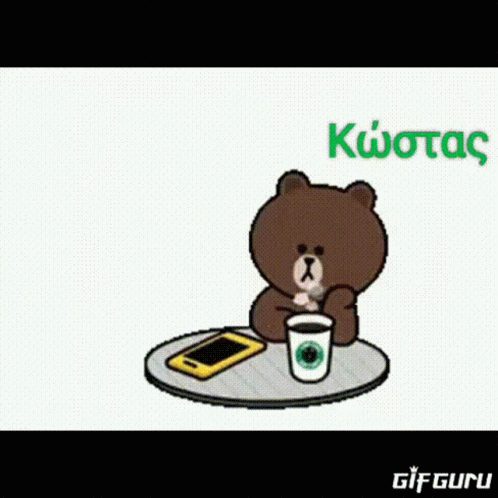 a bear sitting at a table with a cup and phone