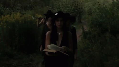 two women with hats and dark clothes reading the book