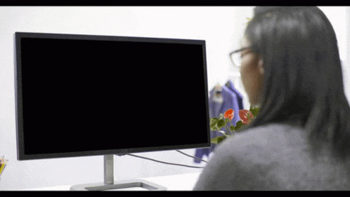 a woman standing by a computer screen with her eyes closed
