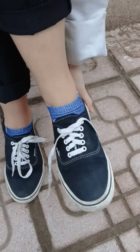 legs and shoes of two people with socks and blue pants on