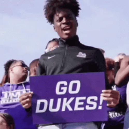 a man holding a sign that reads go dukes