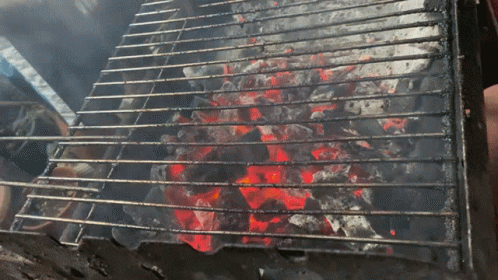 a closeup of blue flames cooking on an outside grill