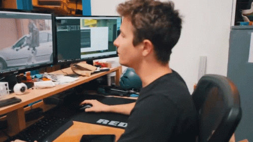 a man sitting at a computer and looking at his computer screen