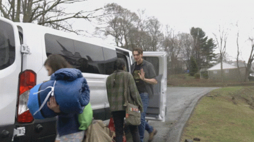 a group of people carrying backpacks out of an rv