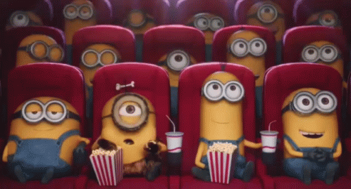 two cute little minion sitting in the aisle of a movie theater
