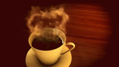 a steaming cup of coffee on a plate on a table
