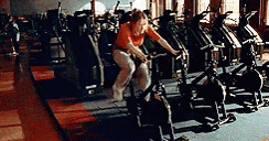 woman in gym on bike with people watching from behind