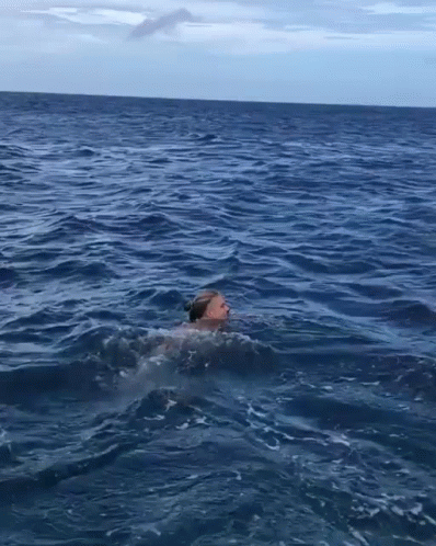 a man swimming in the water at dusk