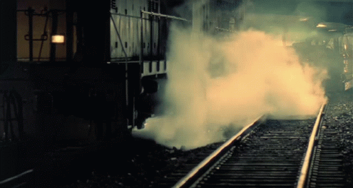 steam rises from the side of a train track