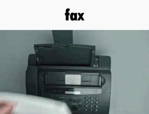 a fax machine in front of a laptop sitting on a desk