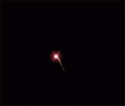 a white object flying in the dark on top of a field