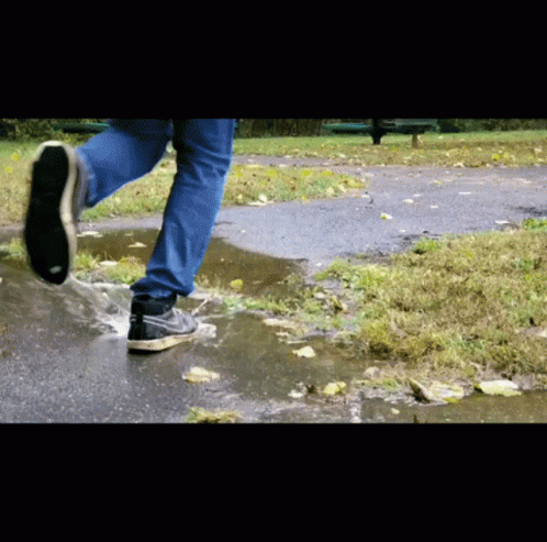 a person walking over a sidewalk with water dles on it
