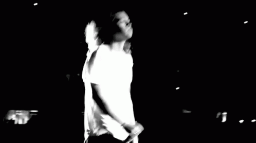 blurry black and white po of a man in white on stage