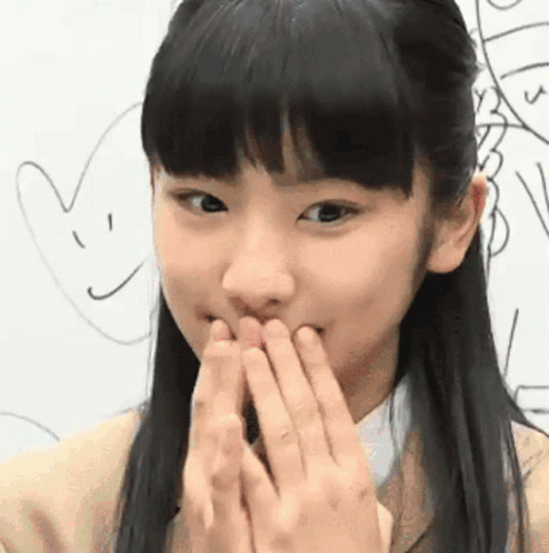 an asian girl covers her mouth with her hands