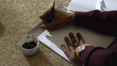 person writing in notebook with scissors and glue