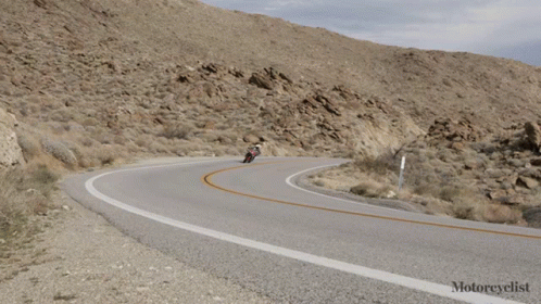 motorcycle riders travel along a curvy mountain road