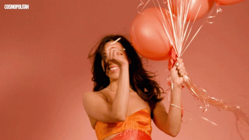 the woman holds several balloons in her hands