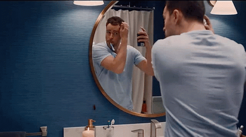 a person standing in front of a mirror brushing their teeth