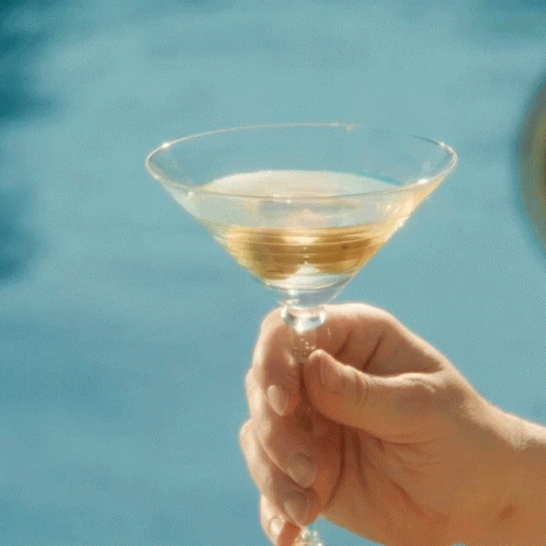 a hand holding a martini glass with blue liquid