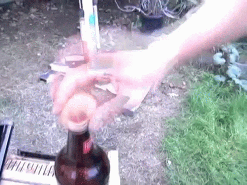 a hand reaching for a bottle of alcohol outside