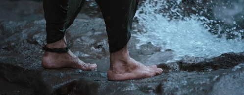 feet in white shoes next to waterfall of water