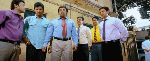 six men standing in a row, with one man wearing a tie and the other a dress shirt