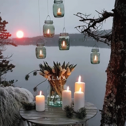 a table topped with white candles sitting next to trees