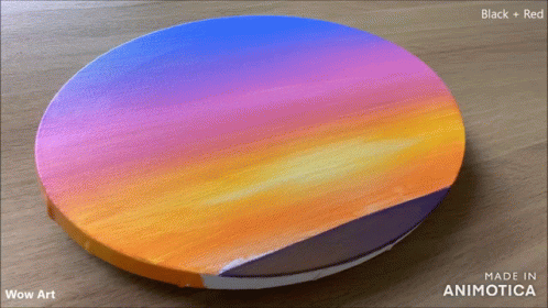 an orange, pink and blue painting on top of a wooden table