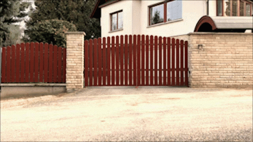 an automatic sliding gate with a long blue fence and gated entrance