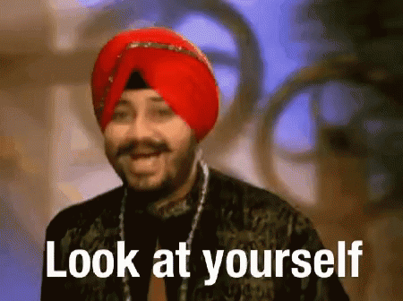a man with a blue turban smiling and standing in front of a sign that says look at yourself
