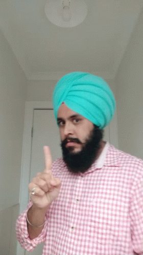 man with black hair and a turban pointing at soing