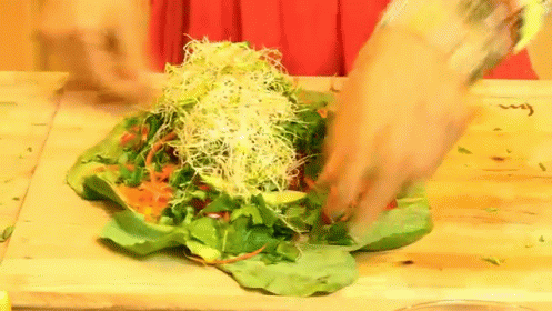a man is chopping a sprout salad into smaller squares on top of a table