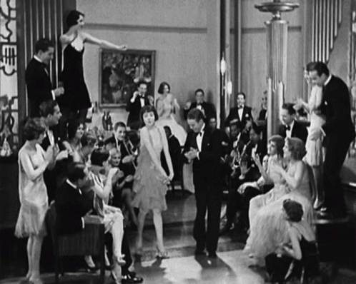two woman in a black and white po dancing with a group of people around them
