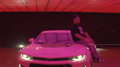 a man riding on the hood of a pink car
