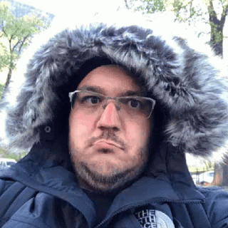 a man with a beard wearing glasses and a parka coat