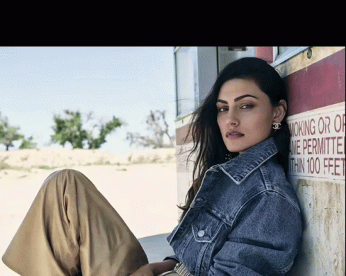 a woman in denim clothes posing against a wall