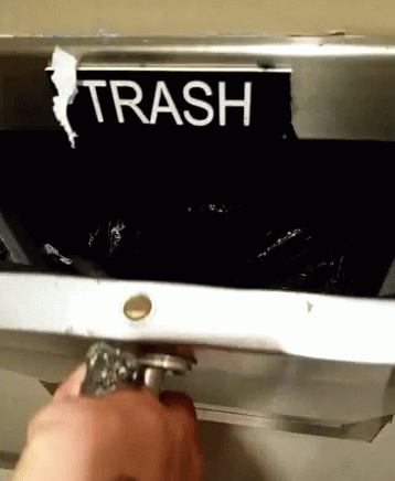a hand removing trash from a garbage disposal machine