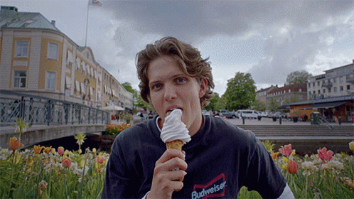 man eating an ice cream cone in a park