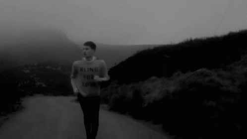 man running down road in dark black and white