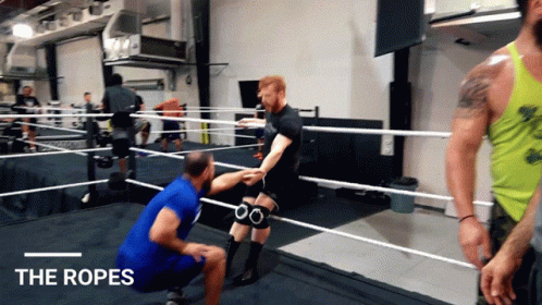 people are standing around wrestling rings in a gym