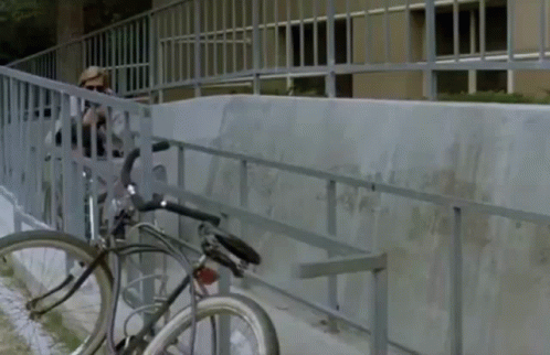 a bicycle is  to the side of a fence