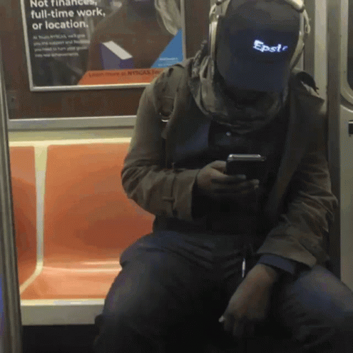a man wearing an electronic device while sitting on a subway